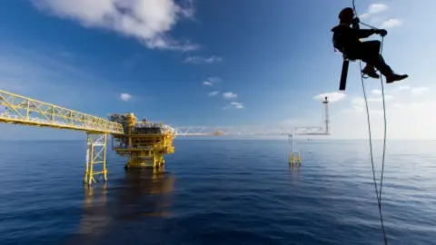 persoon aan kabels bij booreiland