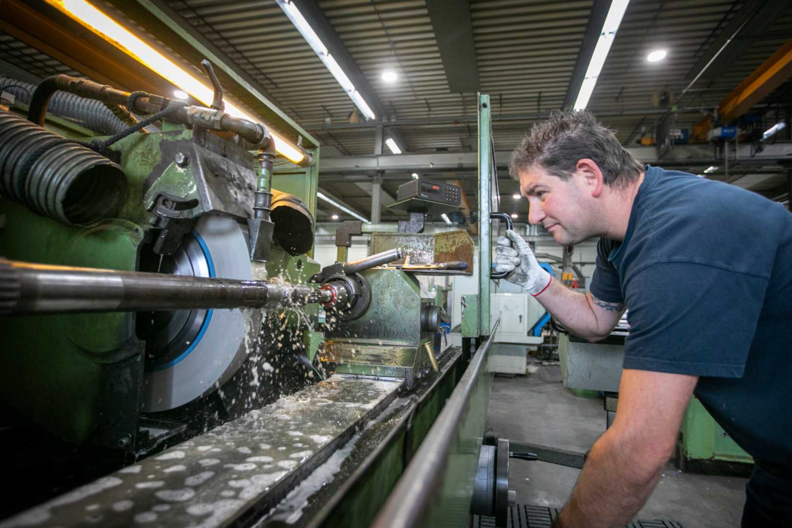 Rondslijpen Man staat bij rondslijpmachine